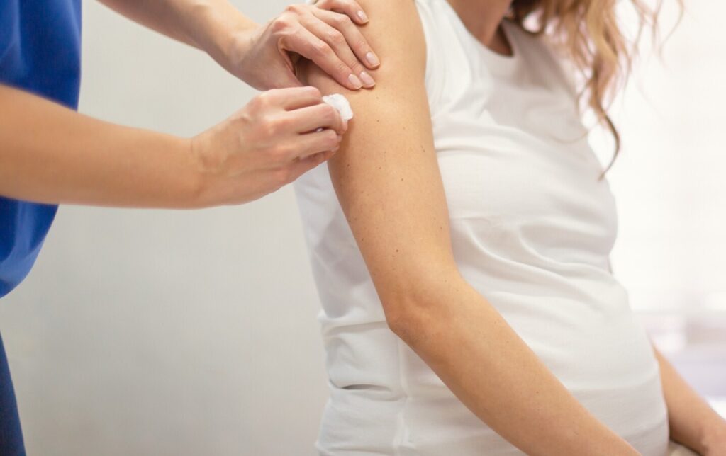 pregnant woman being prepped for a vaccination by a healthcare professional