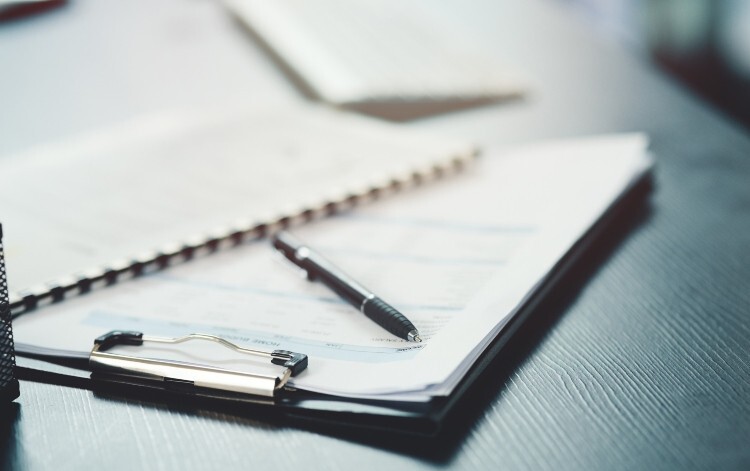 Clipboard, paper and pen on a table