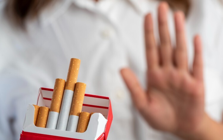 Someone says no to a packet of cigarettes being held out to them
