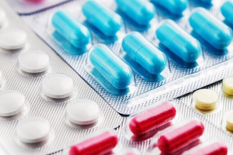 Heap of medical pills in white, blue and other colours. Pills in plastic package.