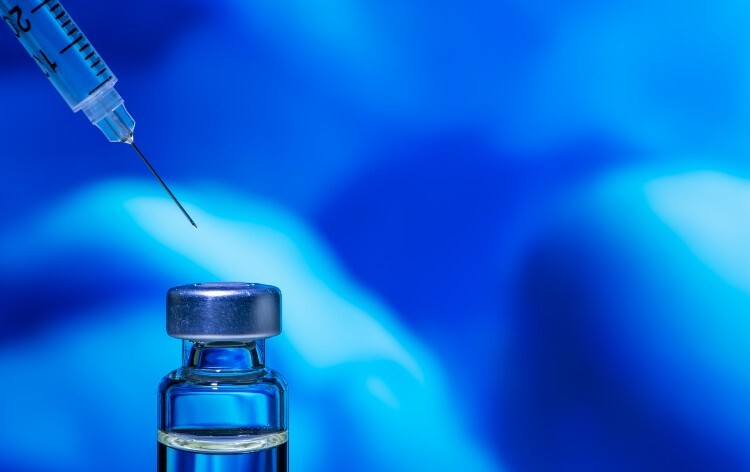 Syringe and vial of medicine with a blue background