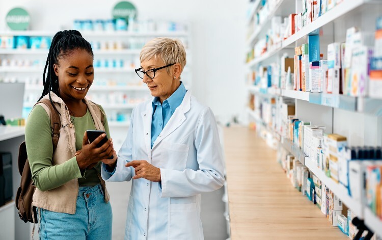 A pharmacist and a woman looking at a phone inside a pharmacy