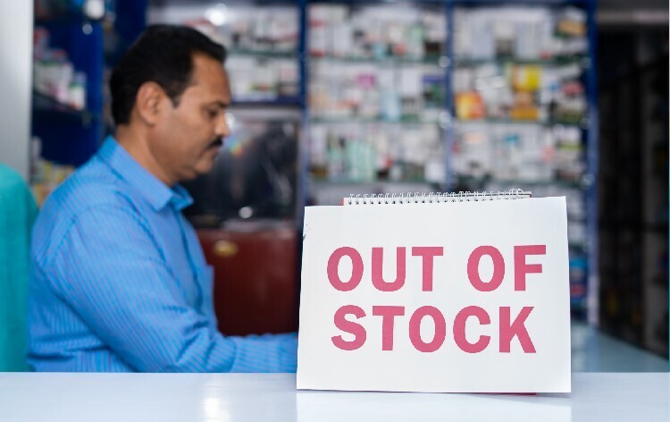 Pharmacist sat at desk next to out of stock sign