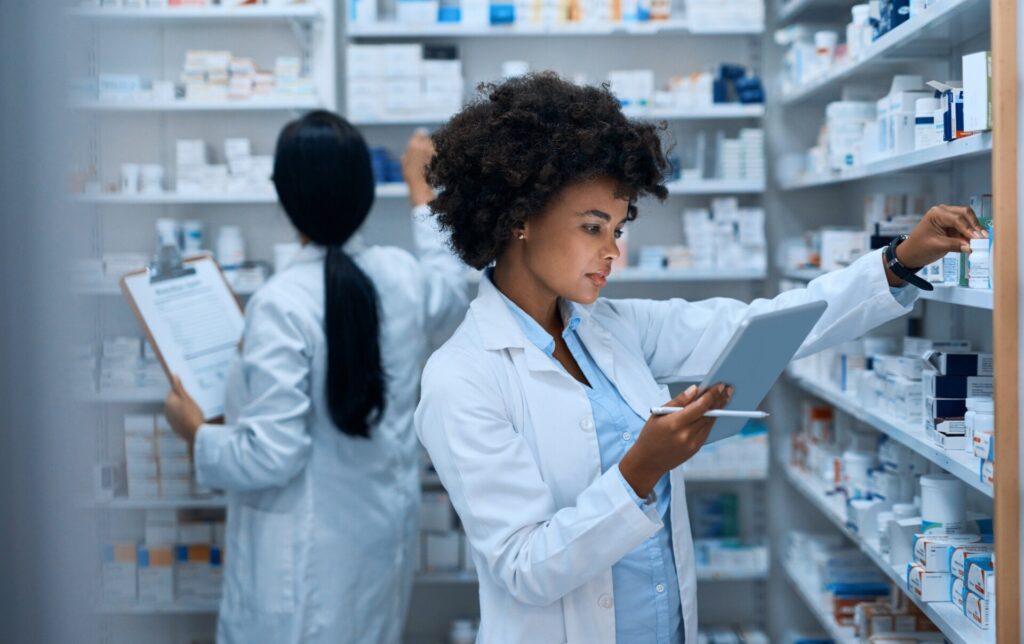Two pharmacists looking at medicines shelves