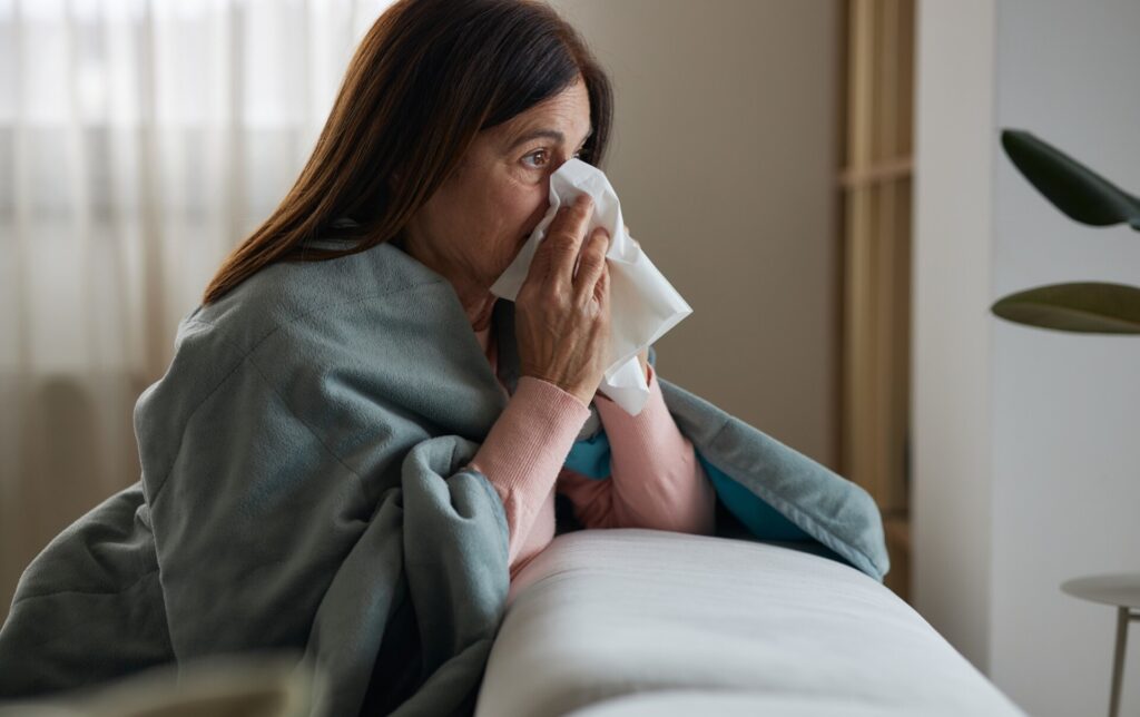 Woman in bed blowing her nose with the flu