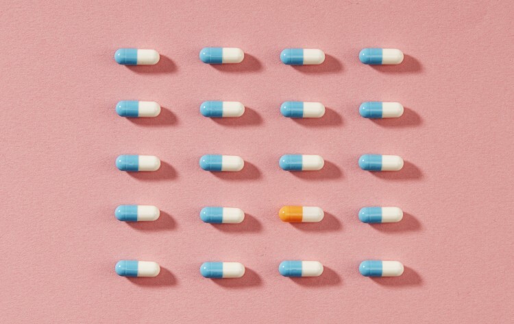 blue and yellow pills on a pink background