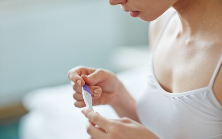Teenager looking at positive pregnancy test