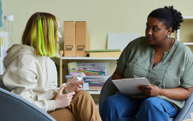Female community worker talking to teenage girl at office