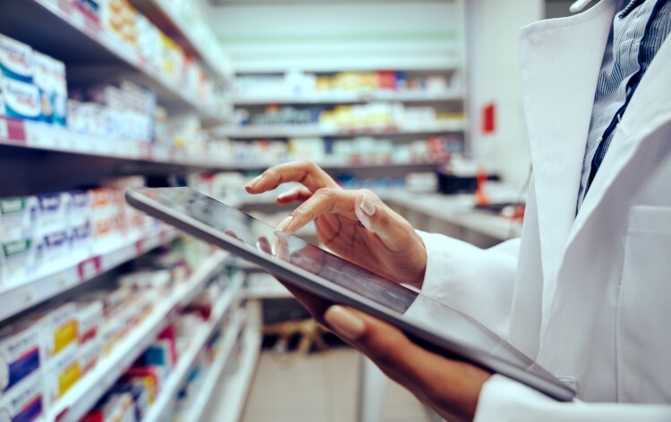 Pharmacist holding a tablet inside a pharmacy