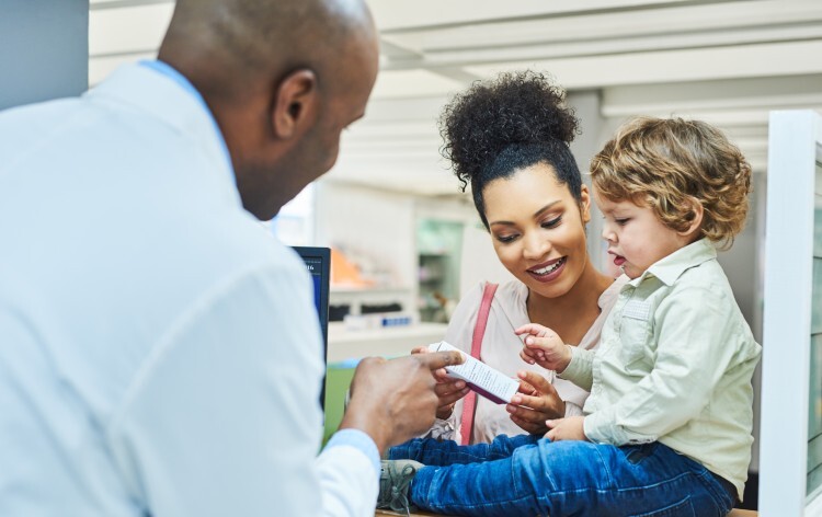 Pharmacist assisting a young woman and her young son in a chemist