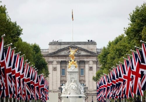 The front of Buckingham Palace with union jack flags