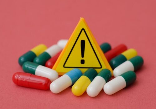 Yellow Warning Exclamation Sign Surrounded by Medical Capsules