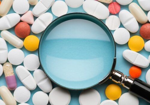 Pills around a magnifying glass