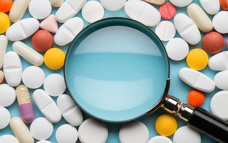 Pills around a magnifying glass