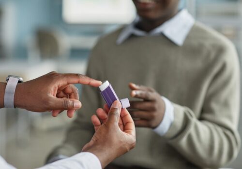 Young Adult Black Man Receiving Asthma Inhaler from Medical Professional