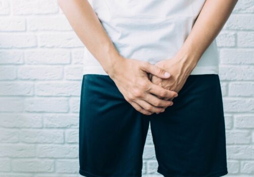 Man wearing shorts holding genitals. Men's health, venereologist, sexual disease