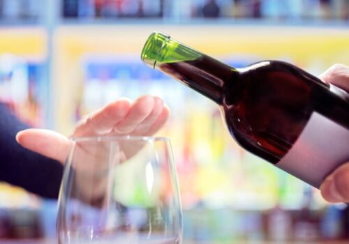 Woman rejecting more alcohol from wine bottle in bar