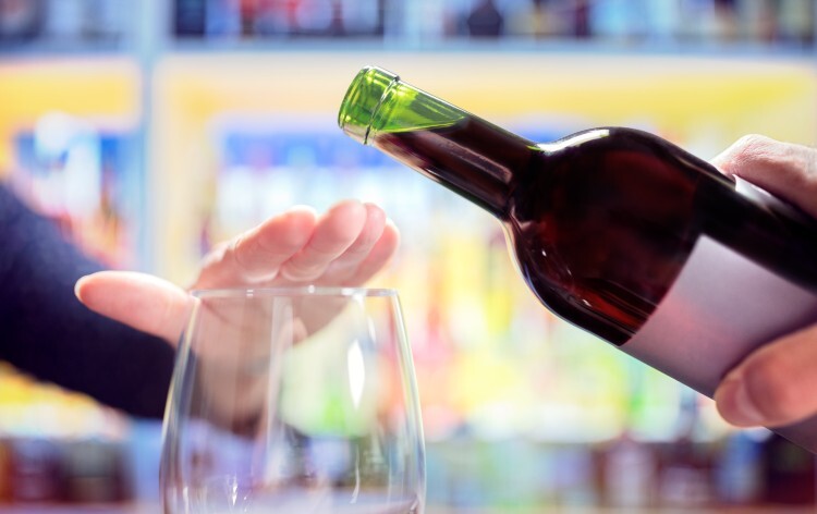 Woman rejecting more alcohol from wine bottle in bar