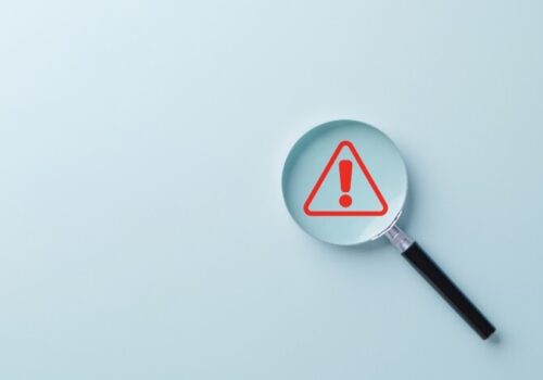 Warning Alert Symbol. A red warning symbol under magnifying glass, symbolizing risk detection, safety alerts, issue investigation, or system monitoring in business and technology contexts