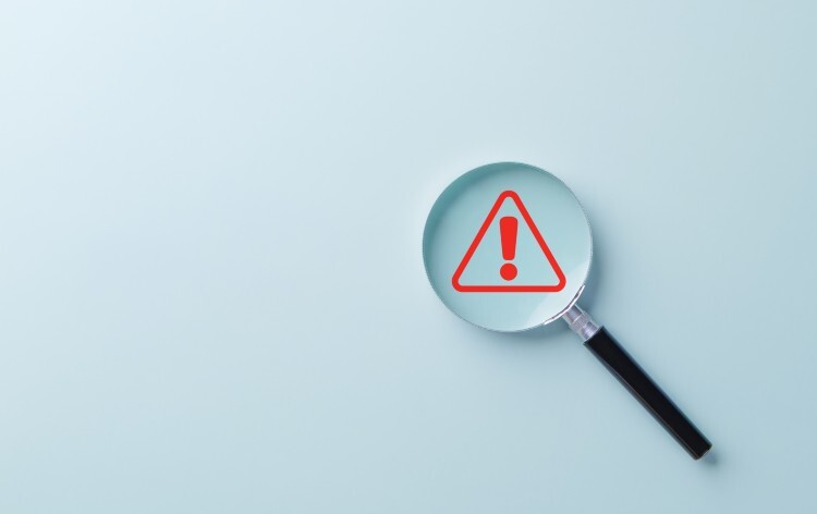 Warning Alert Symbol. A red warning symbol under magnifying glass, symbolizing risk detection, safety alerts, issue investigation, or system monitoring in business and technology contexts
