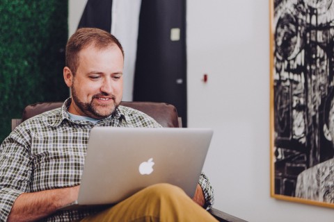 Man smiling using mac book
