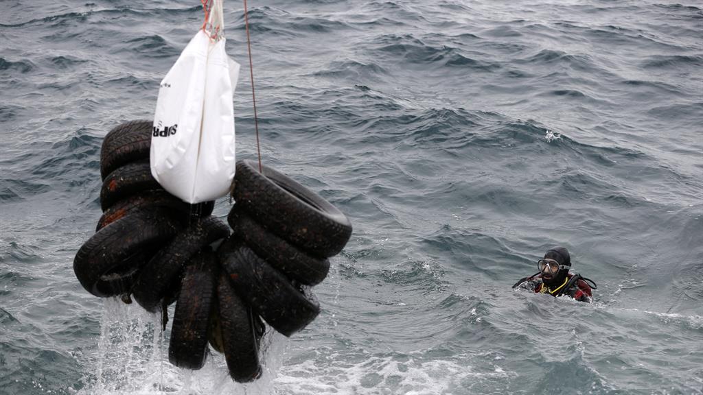Bundle: A diver gathers tyres PICTURES: AP