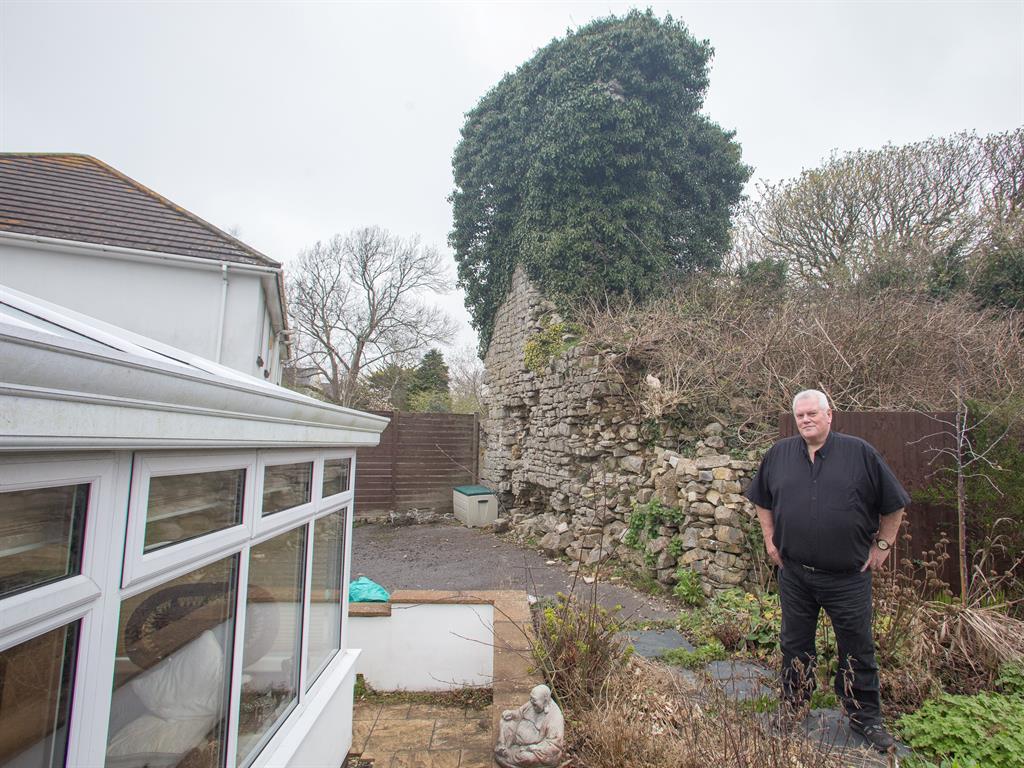 Looming threat: Rob Stockdale in front of the precarious remains of the castle which towers over his home in Llanmaes, Wales PICTURES: SWNS