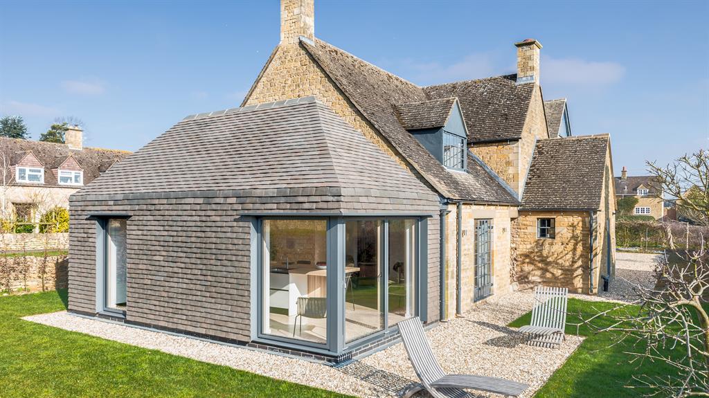 Side project: The single-storey ‘outbuilding’ extension houses the new kitchen and is clad in bespoke tiles spanning the roof and walls, designed to shed water to a channel drain – meaning guttering isn’t required