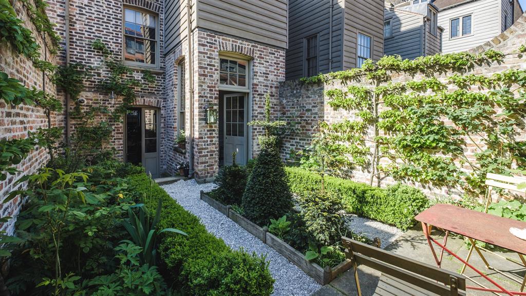 No parking: The garden, once a car park, has now been reclaimed with espalier trees climbing up the walls. Bespoke touches, such as the old-fashioned taps, inset, add to the character
