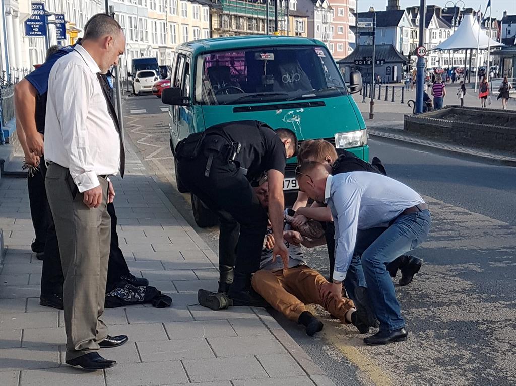 Held down: The moment police arrest Neil Jones outside the wedding venue PICTURE: SWNS