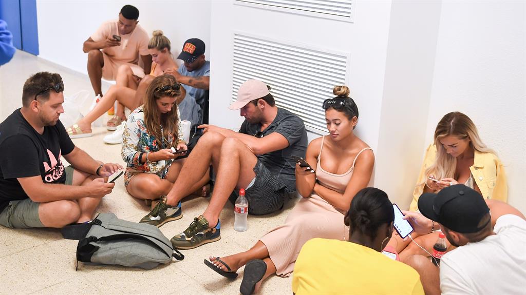 Phone frenzy: Islanders get back in touch with the outside world and (below) arriving at Stansted