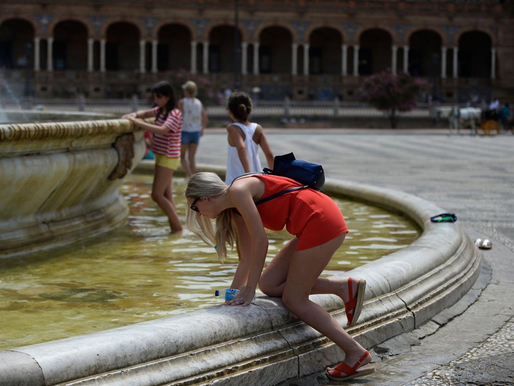 Feeling the heat: A woman refreshes herself in a fountain at Plaza de Espana, on a hot summer day in Sevilla PICTURE: GETTY