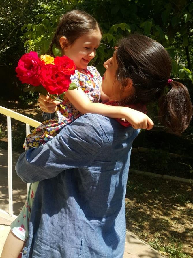 Hugs: Gabriella greets her mother with a bunch of flowers