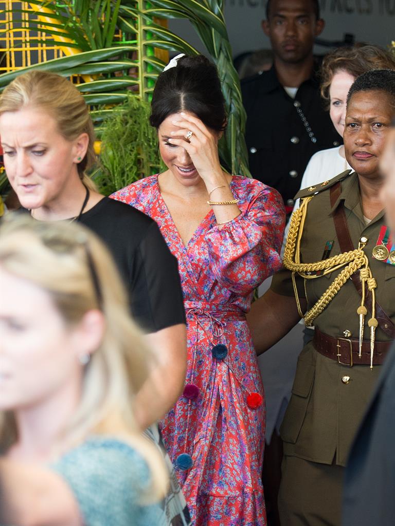 Taking a breather: Meghan appears to feel the strain as she is escorted out of the market