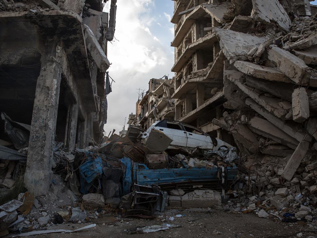 Carnage of war: Crumpled cars amid rubble in the boy’s former home city of Homs PICTURE: GETTY