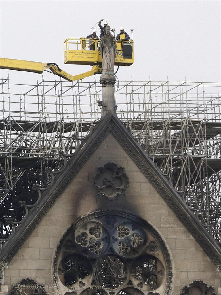Removal men: Experts prepare to lift a statue from the damaged cathedral roof