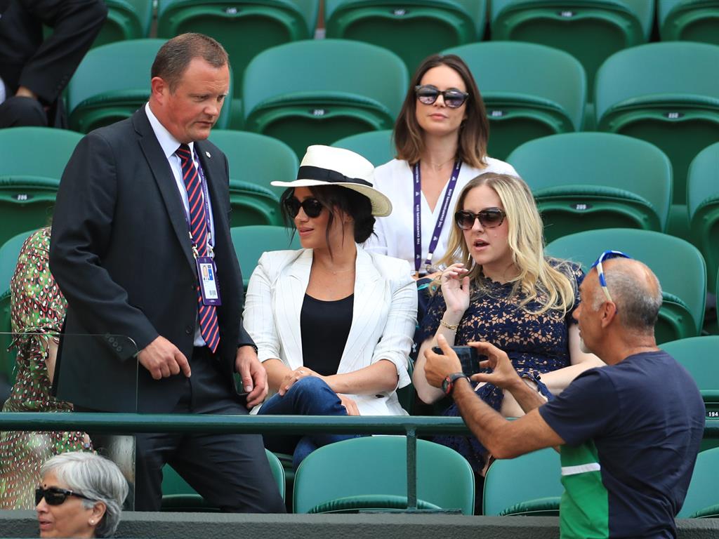 Stop what you're doing: The bodyguard notices Mr Hasanov pointing his phone in Meghan's direction and comes over to have words (below)