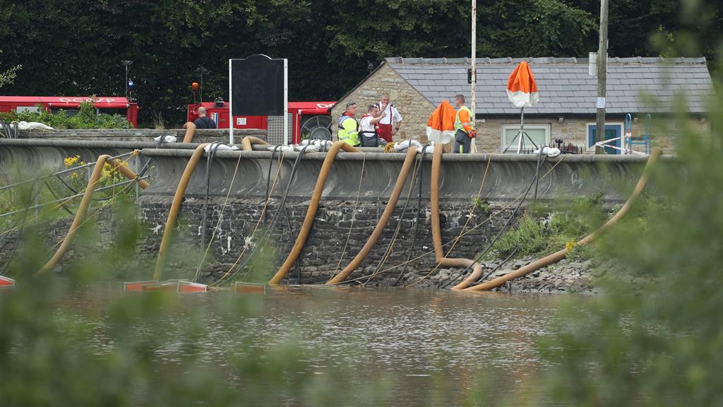 Round the clock: Workmen pump water from Toddbrook reservoir near the village of Whaley Bridge