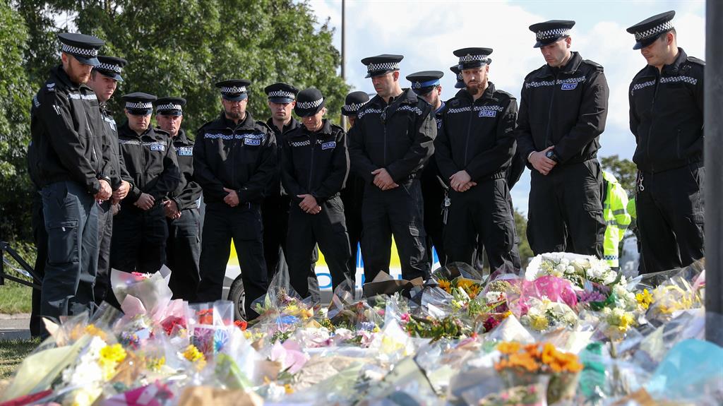 Fallen colleague: Police officers stand in silence as they view the flowers and tributes to PC Harper PICTURE: PA