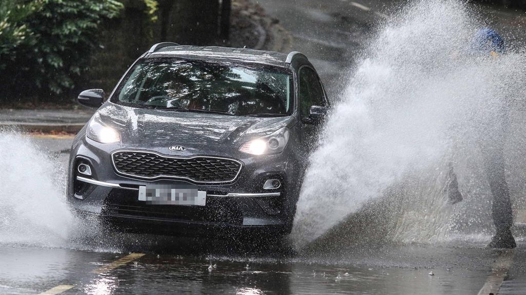 Splish splash: A dog walker gets a soaking as a motorist drives through floodwater in Barrow Bridge in Bolton PICTURE: SWNS