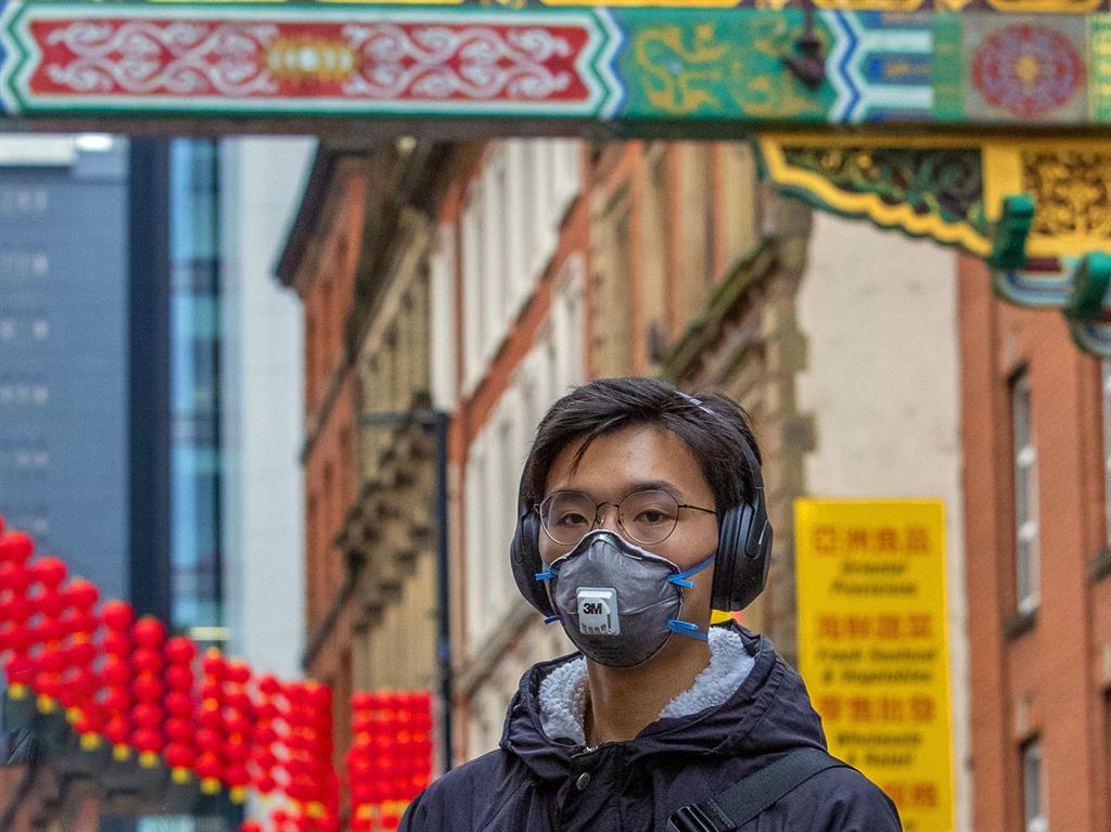 Precaution: A member of the Chinese community in Manchester wearing a face mask PICTURE: PA