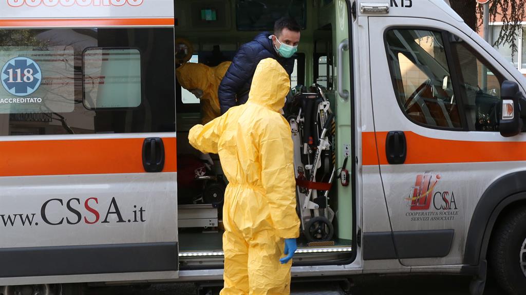 Step down: A health worker escorts a potential coronavirus victim out of an ambulance outside the Padua hospital in northern Italy PICTURE: EPA
