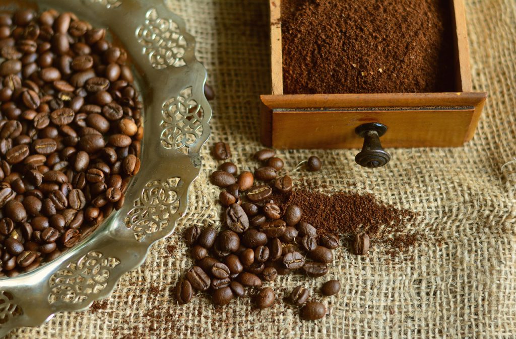 coffee beans in a dish, ground coffee in a drawer and some on the table