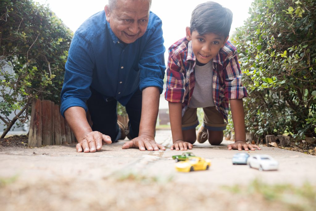do dads ever grow up? Grandad playing toy cars with grandson