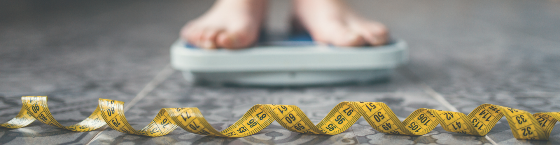 feet on bathroom scales and a measuring tape on the floor