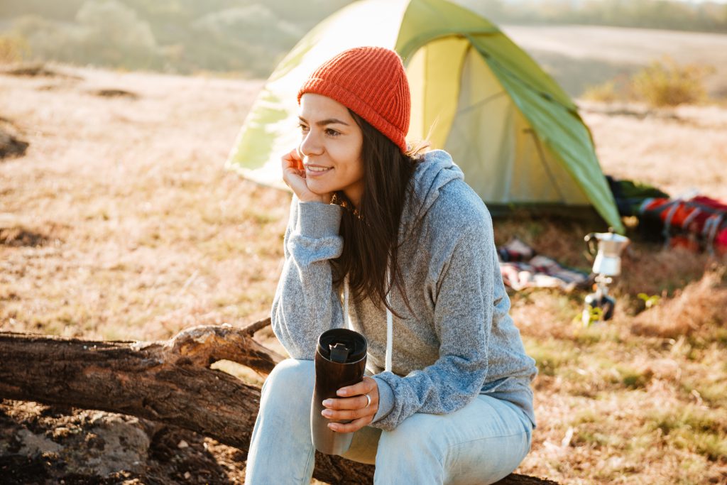 Woman sat with a coffee outside a tent
