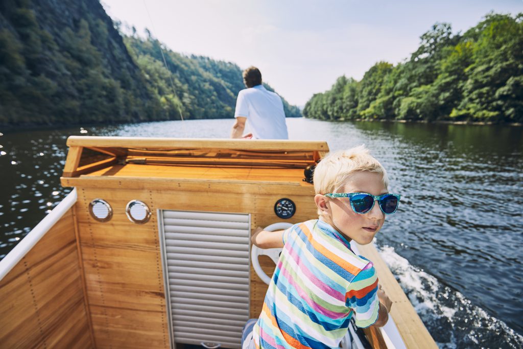 Boating Holidays with Children - young boy steering a motor boat