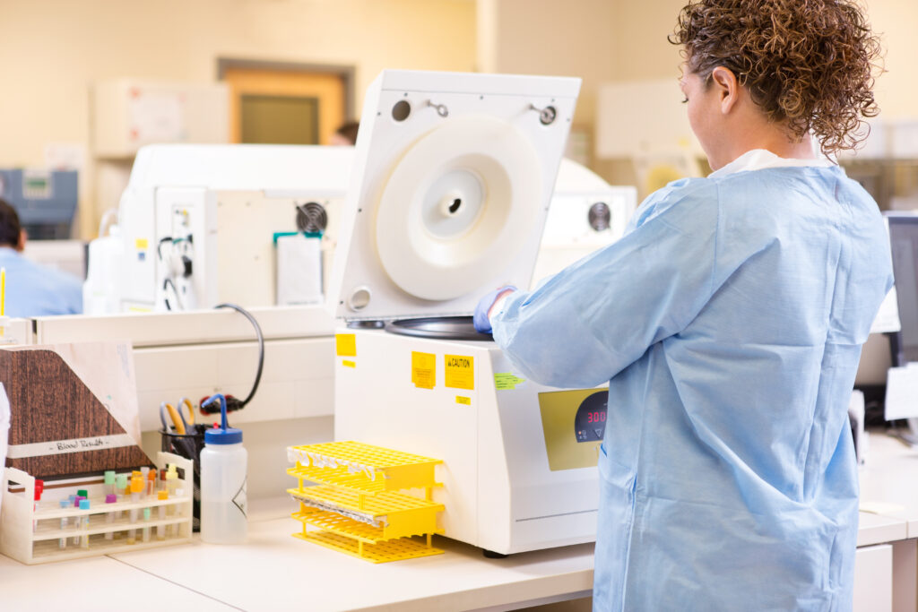 Rear view of female scientist using PCR machine in laboratory to check DNA before cord blood banking