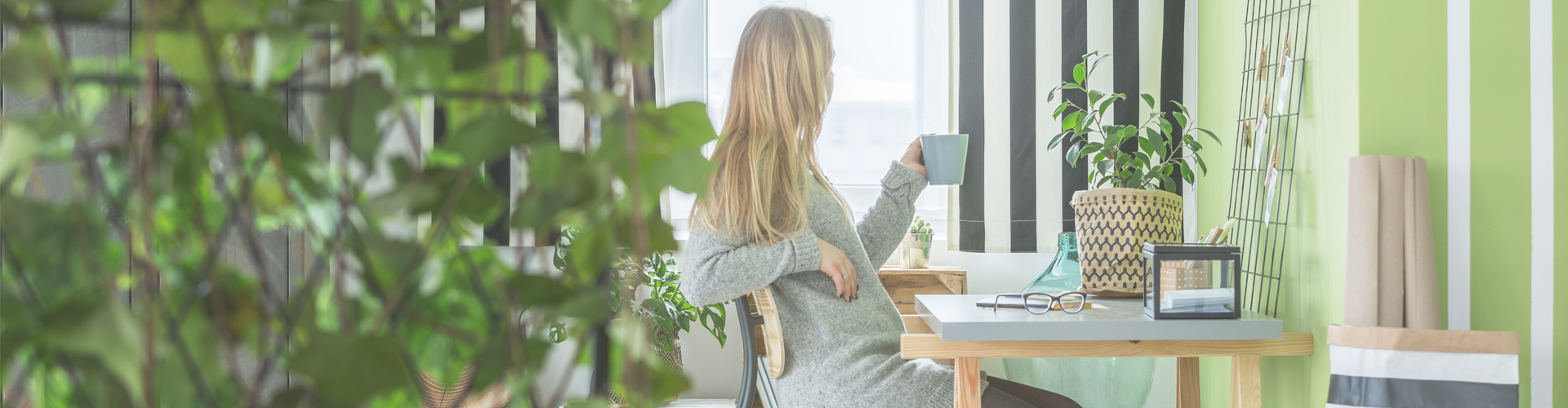woman looking out of window while drinking coffee in home office... Ways to save money when working from home