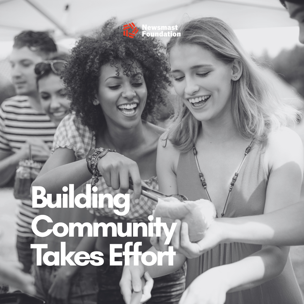 A black and white image of two women at a barbecue sharing food. Over it, text reads: Building Community Takes Effort. Newsmast Foundation.
